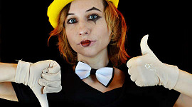 một người phụ nữ trẻ đeo nơ và đeo găng tay trắng với khuôn mặt chú hề đang giơ ngón tay cái lên và không thích
