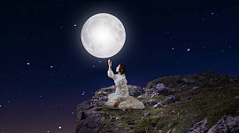 mujer sentada bajo la luna llena y las estrellas