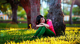μια νεαρή γυναίκα που κάθεται και στηρίζεται σε ένα δέντρο