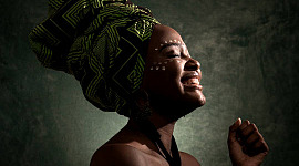 African woman wearing a headress with eyes closed and smile