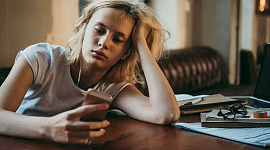 pozbawiona energii kobieta wpatrująca się w swój telefon