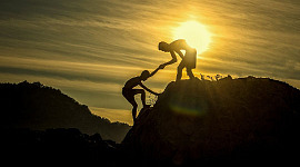 två klättrare, där den ena ger den andra en hjälpande hand