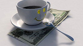 una taza con una cara sonriente y café encima de un billete de 100 dólares estadounidenses