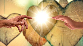 two hands reaching out to each other in front of a brightly shining heart