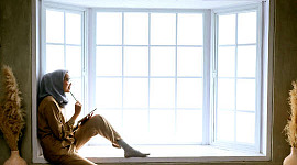 eine Frau, die in einem Erkerfenster sitzt