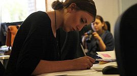 woman sitting at a desk working while someone in the background is not working