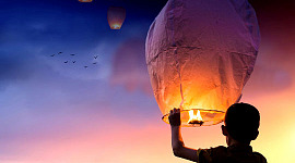 a young boy releasing lit-up balloons into the sky