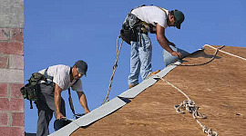 deux hommes travaillant sur un toit