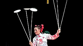 seorang wanita menyeimbangkan serangkaian piring pada tongkat