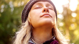 ung kvinne med lukkede øyne, ansiktet opp mot himmelen