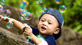 seorang anak laki-laki dikelilingi oleh gelembung sabun