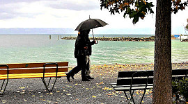 um casal andando na chuva sob um guarda-chuva