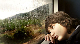 jonge jongen die peinzend uit een raam kijkt