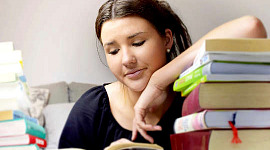 en ung kvinne som fredelig leser en bok med armen hvilende en hel bunke bøker
