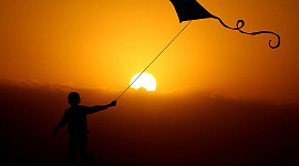 een kind vliegeren bij zonsondergang