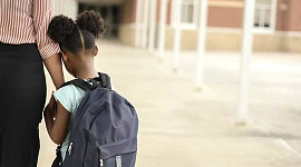 una madre sosteniendo la mano de su hija cuando regresa a la escuela