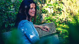 kvinde sidder fredeligt på en bænk ude i naturen