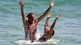 、喜びで空中に手を上げて海にいる男女