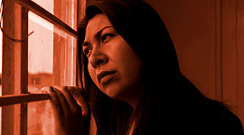en kvinna som tittar ut genom ett fönster