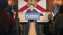 Ron De Santis na podium z napisem: Floryda, stan edukacji
