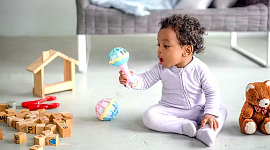 en baby, der sidder på gulvet og leger med legetøj