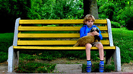 ung pojke sitter på en bänk och håller ett husdjur