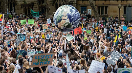 manifestanti che sorreggono un grande globo del Pianeta Terra