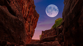 a full moon surrounded by red rock