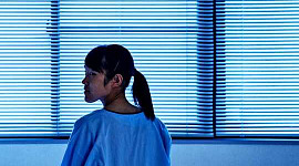 Una mujer joven sola en una habitación de hospital.