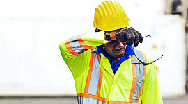 Um trabalhador da construção civil enxuga a testa com o calor