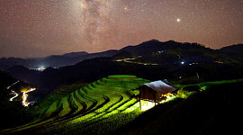 fel licht van onder een klein gebouw lichte terrasvormige rijstvelden onder de sterrenhemel