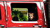 Le visage de l'enfant dans la fenêtre de la cabine allongée du camion rouge