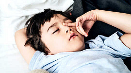 En ung gutt gnir seg i øynene mens han legger seg i sengen