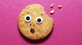 A surprised cookie with eyes and a mouth has one bite taken out it
